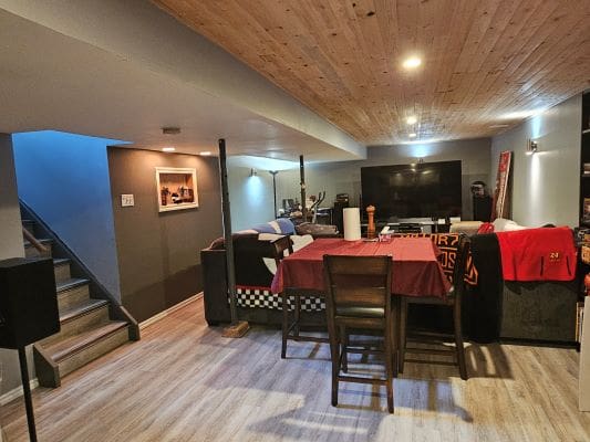Basement lounge with TV and wooden ceiling.