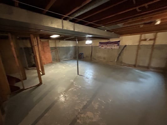 Unfinished basement with exposed beams and concrete floor.