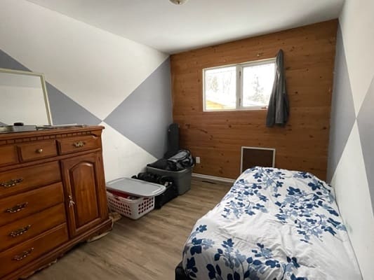 Small bedroom with bed and wooden dresser.
