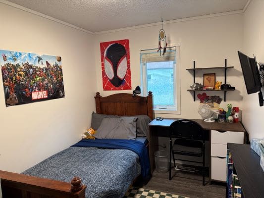 Bedroom with superhero-themed decor and desk.