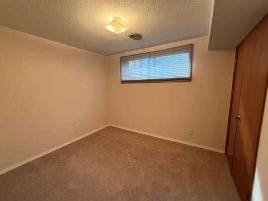 Empty room with carpet and window blinds.