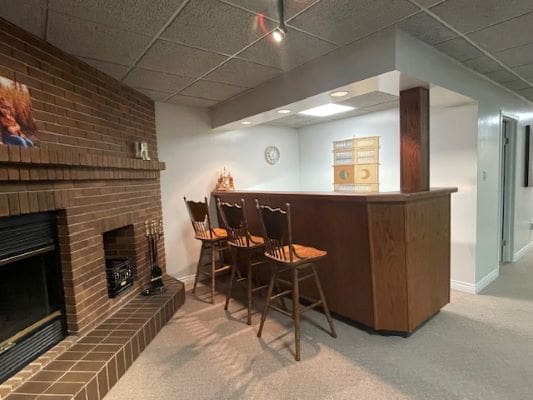 Basement bar with brick fireplace and stools.