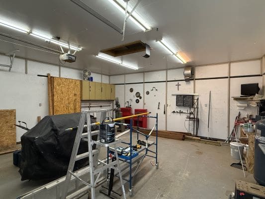 Workshop with tools, covered equipment, and ladder.