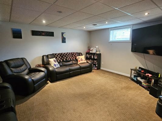 Cozy basement with leather seating and TV.