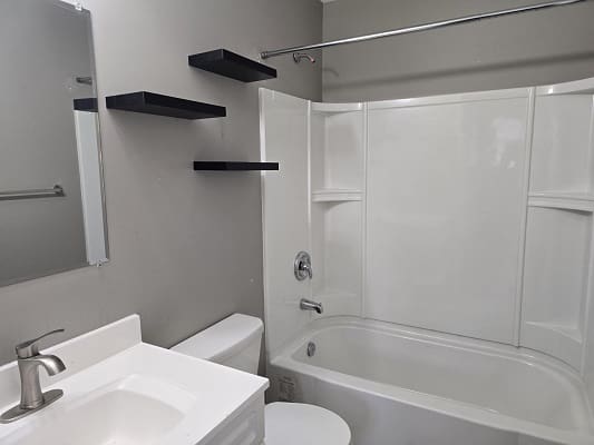 Modern bathroom with bathtub and floating shelves.
