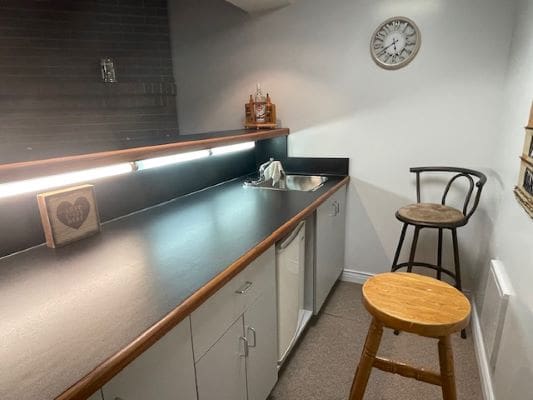 Small kitchen with bar stools and clock.