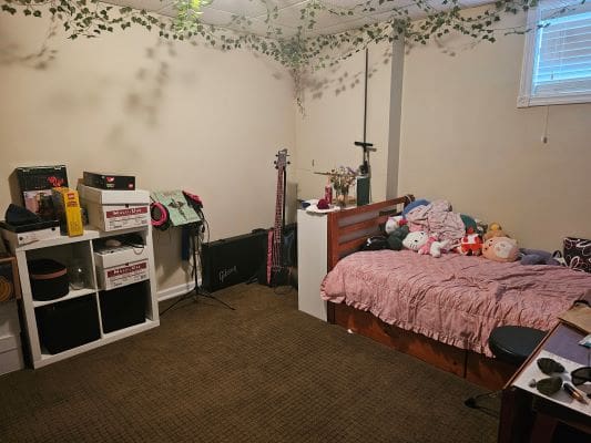 Cozy bedroom with stuffed animals and guitar.