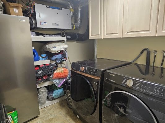 Laundry room with washer, dryer, and shelves.
