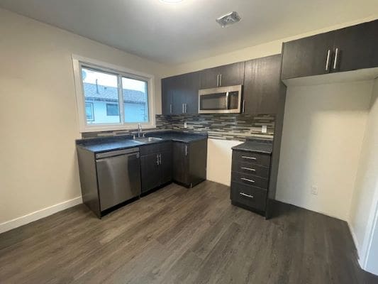 Modern kitchen with dark cabinets and appliances.