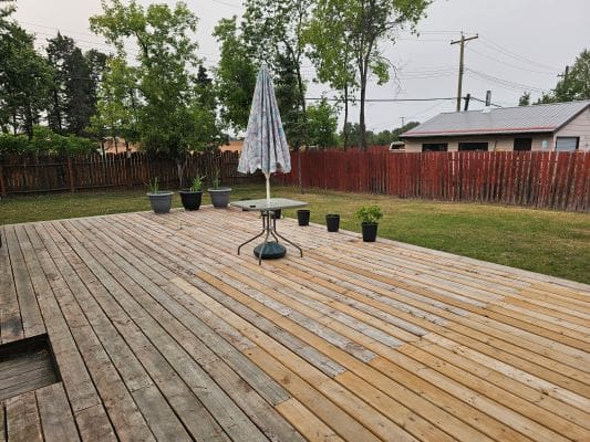 Wooden deck with potted plants and umbrella.