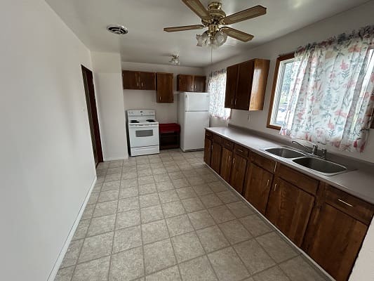Spacious kitchen with wooden cabinets and tiles.