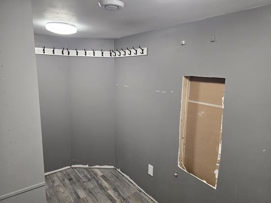 Small empty gray room with coat hooks.
