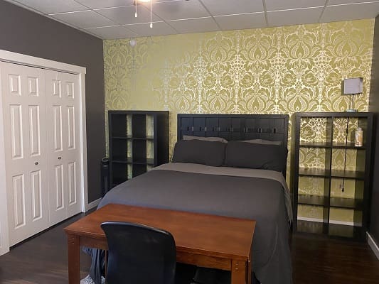 Bedroom with bed, desk, and decorative wallpaper.