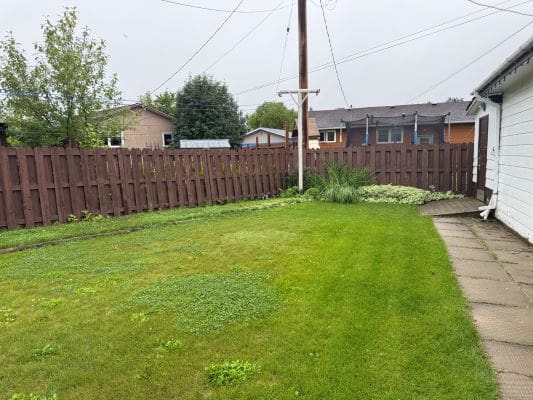 Green backyard with wooden fence and pathway.
