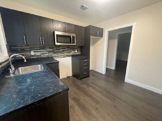 Modern kitchen with dark cabinets and flooring.