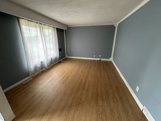 Empty room with wooden floor and curtains.