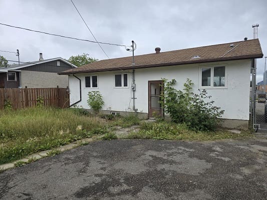 Small house with overgrown backyard.