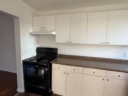 White kitchen cabinets with black stove.
