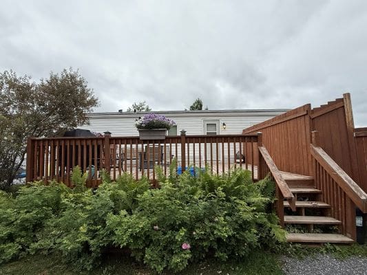 Wooden deck with stairs and greenery.