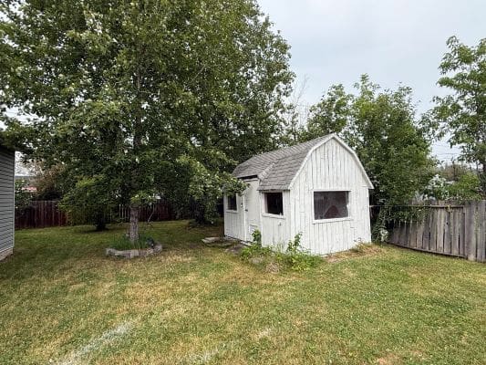 Small white shed in grassy backyard.