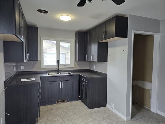 Modern kitchen with dark cabinets and window.