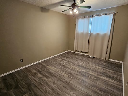 Empty room with wooden floor and curtains.