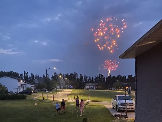Fireworks display over suburban neighborhood at dusk.