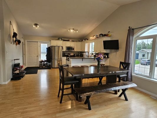 Spacious kitchen with dining table and flowers.