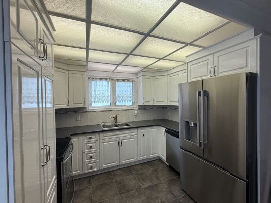 Modern kitchen with white cabinets and appliances.