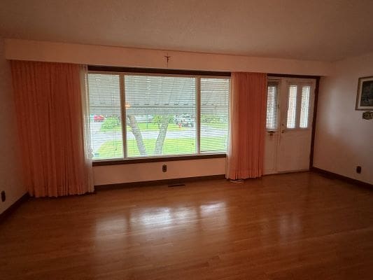 Empty room with large window and curtains.