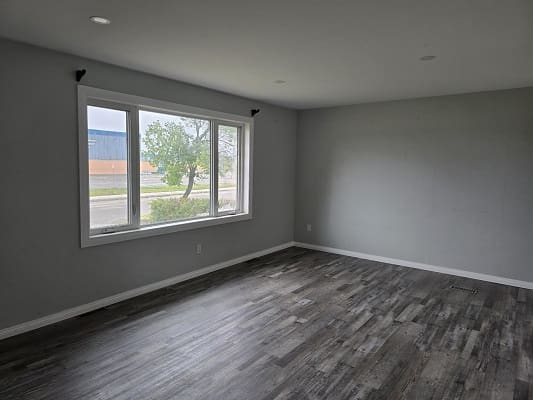 Empty room with large window and flooring.