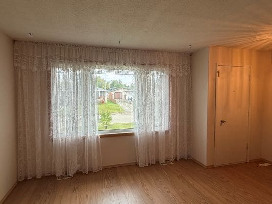 Empty room with large window and curtains.
