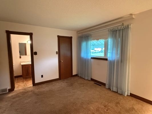 Empty room with window and bathroom door.