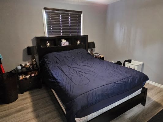 Bedroom with dark bedspread and furniture.