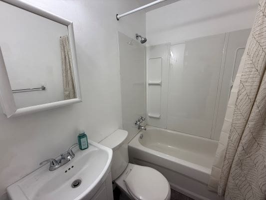 Small white bathroom with bathtub and sink.