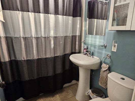Small bathroom with striped shower curtain.