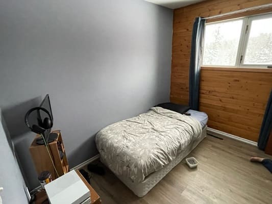 Simple bedroom with bed and wooden wall.