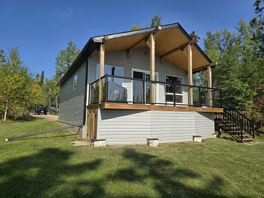 Small house with porch in wooded area.