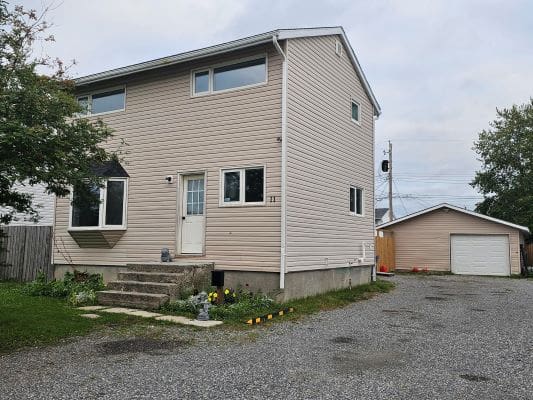 Two-story house with gravel driveway.