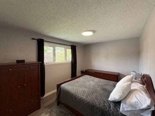 Small bedroom with bed and dresser.