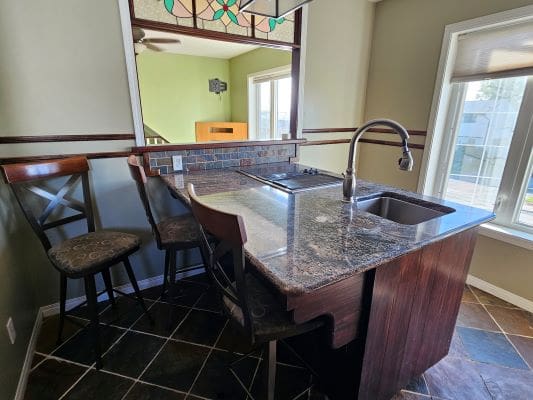 Kitchen island with chairs and sink.