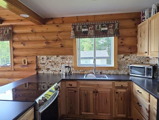 Wooden kitchen with stove and microwave.