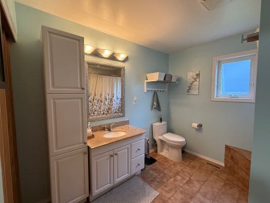 Light blue bathroom with white cabinets.