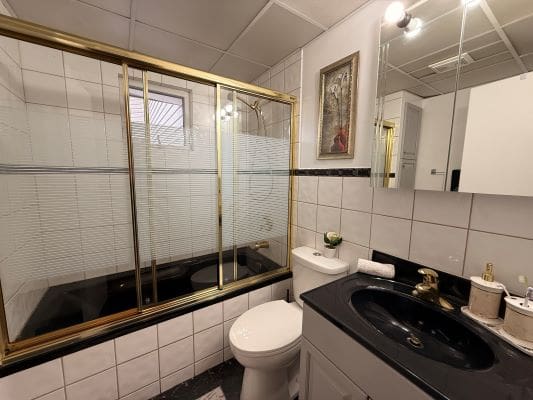 Modern bathroom with black countertop and shower.