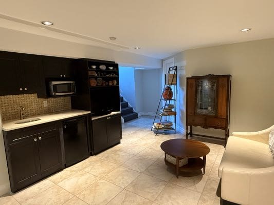 Basement kitchenette with seating and shelving unit.
