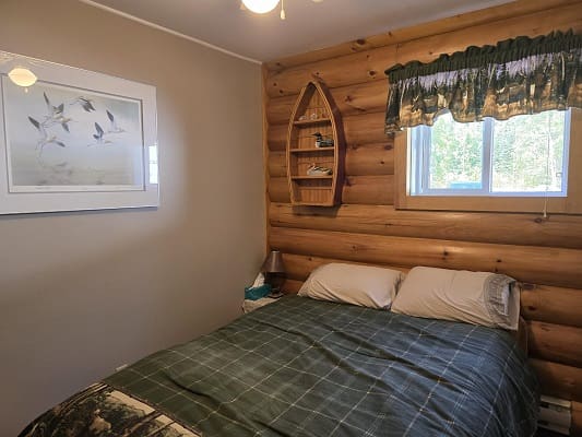 Cozy log cabin bedroom with window view.