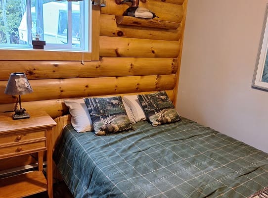 Log cabin bedroom with plaid bedspread.
