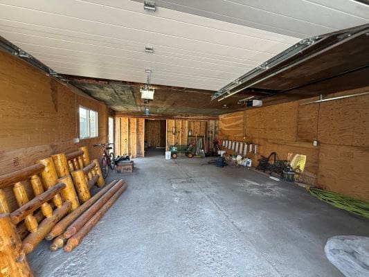 Spacious garage with wooden beams and tools.