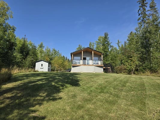 House with lawn surrounded by trees.