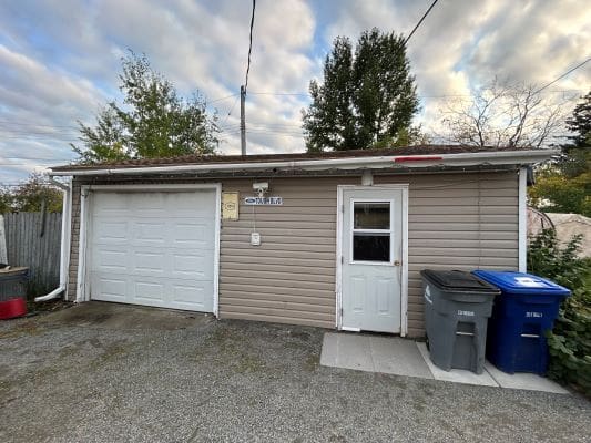 Garage with bins and cloudy sky.